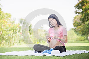 Chreeful pregnant woman sitting relax in the park and knits crochet