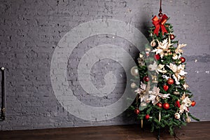 Chrismass tree with red bals and bow in fornt of bricks wall