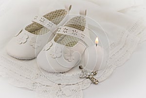 Christening booties invitation background with white lace, candle and crystal cross pendant photo