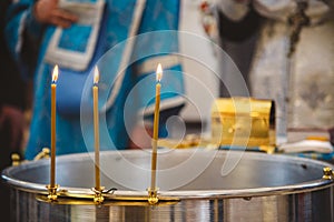 Christening in the church, candles at children baptismal font. Details in the orthodox christian church