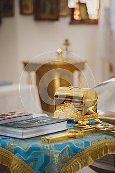 Christening in the church, golden religious utensils: bible, cross, prayer book, missal. Details in the orthodox christian church