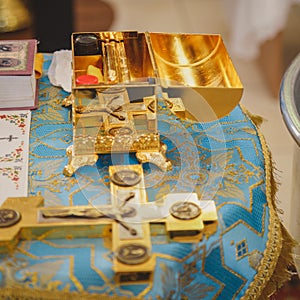 Christening in the church, golden religious utensils: bible, cross, prayer book, missal. Details in the orthodox christian church