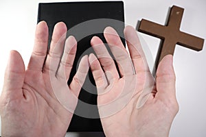 Christian Bible, Hands and Wooden Cross on a White Background