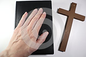 Christian Bible, Hands and Wooden Cross on a White Background