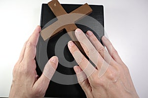 Christian Bible, Hands and Wooden Cross on a White Background