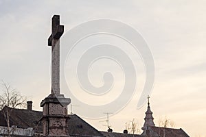 Christian and Catholic crosses, one on a calvary, one on a catholic church, at sunset.