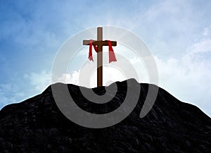 Christian cross against the cloudy sky over the mountains sun behind