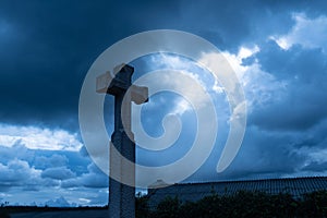 Christian cross against dramatic gloomy dark sky, with sunbeams coming through gloomy clouds of great flood, concept of last photo