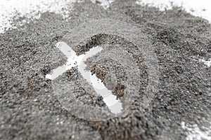 Christian cross or crucifix drawing in ash, dust or sand as symbol of religion, sacrifice, redemtion, Jesus Christ, ash wednesday