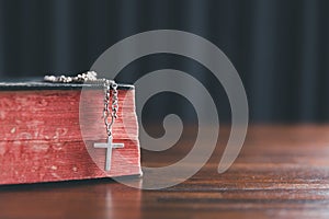 Christian cross crucifix with holy bible background. Wooden Christian cross on grey table against blurred lights, space for text