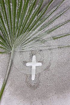 Christian Cross drawing in ash with palm leaf. Concept for Lent Season, Holy Week, Palm Sunday and Good Friday. Flat lay.