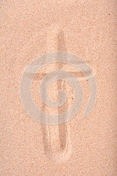 Christian cross drawn in dry sand