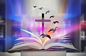 The Christian Cross is illuminated in a book in white and fantasy light, with magic shining as hope, love and freedom in beautiful