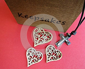 Christian cross with leather cord, decorative wooden hearts and keepsakes box on red background
