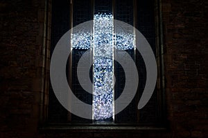 A christian cross made from lights on a church window