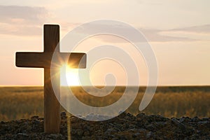 Christian cross outdoors at sunrise, space for text. Religion concept