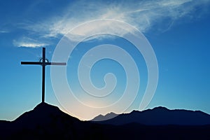 Christian cross over blue sunset background landscape