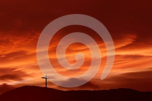 Christian cross over red sunset background landscape