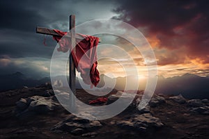 A christian cross with a red cloth, on top of the mountain against sunset light and cloudy sky in a dramatic scenery. Fosus on the