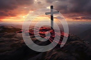 A christian cross with a red cloth, on top of the mountain against sunset light and cloudy sky in a dramatic scenery. Fosus on the