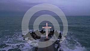 christian cross standing on pier in the sea or ocean with dramatic sky at night