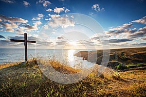 Christian cross on a wild beach and wonderful sunrise