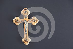 Christian cross on wooden table against black background. Religion concept