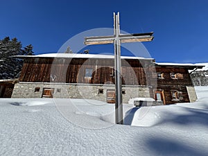 Christian crucifix in the magical winter setting of the Swiss Alps and on the snow-covered alpine pastures the tourist resorts