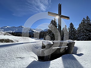 Christian crucifix in the magical winter setting of the Swiss Alps and on the snow-covered alpine pastures the tourist resorts
