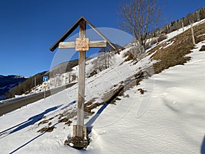 Christian crucifix on the Way of the Cross next to the monastery in a winter atmosphere over the Alpine valley Obertoggenburg