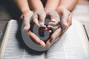 Christian family praying together concept. Child and mother worship God in home. Woman and boy hands praying to god with the bible