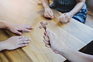 Christian friend show wooden cross to his friends