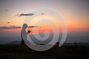 A Christian girl prays to God on top of mountain and sunset. Religious beliefs, Copy space