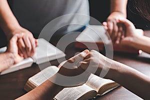 Christian group praying for globe and people around the world on wooden table with bible. Christian small group holding hands and