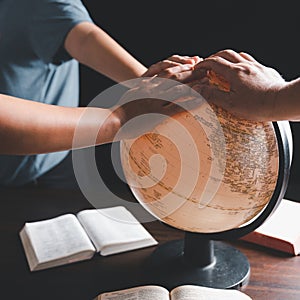 Christian group praying for globe and people around the world on wooden table with bible. Christian small group praying together