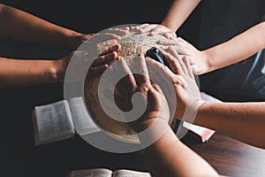 Christian group praying for globe and people around the world on wooden table with bible. Christian small group praying together