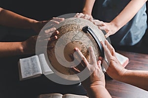 Christian group praying for globe and people around the world on wooden table with bible. Christian small group praying together