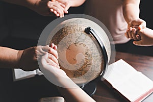 Christian group praying for globe and people around the world on wooden table with bible. Christian small group holding hands and