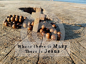 Christian inspirational quote - Where there is Mary, there is Jesus. With wooden Rosary with Jesus Christ holy cross crucifix. photo