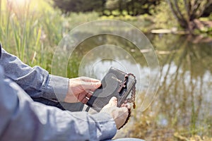 Christian man holding Holy Bible, religious cross and rosary beads by water and field background