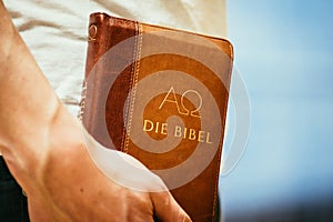 Christian preacher: Young man is holding the bible, praying photo