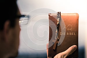 Christian preacher: Young man is holding the bible, praying photo