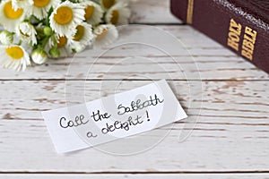 Christian Sabbath rest handwritten note with closed holy bible and flowers on wooden table