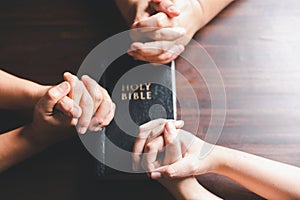 Christian small group praying together around a wooden table with bible page in homeroom. Christian group praying for globe and