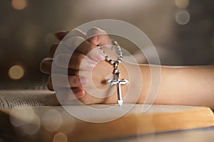 Christian woman hand on holy bible worship to god holding cross rosary