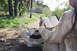 Christian woman holds bible in her hands. Reading the Bible in nature. Concept for faith, spirituality and religion