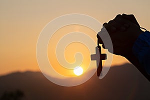 Christian woman praying on holy cross in the morning, teenager woman hand with cross praying,Hands folded in prayer in church