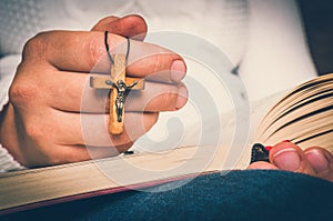 Christian woman with wooden cross reading a holy Bible