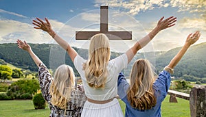 Christian worshipers raising hands up in the air in front of the cross