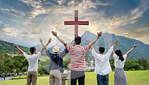 Christian worshipers raising hands up in the air in front of the cross